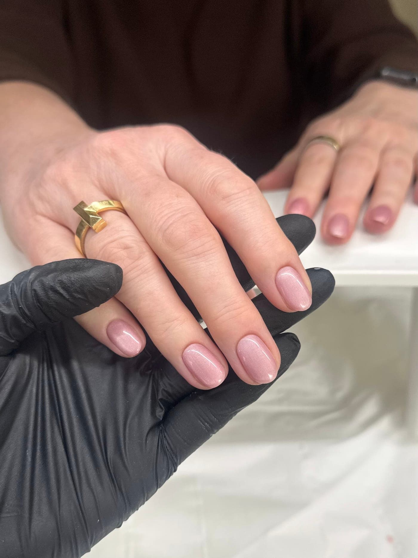 A CREATE technician's gloved hands presenting a shimmer gel manicure