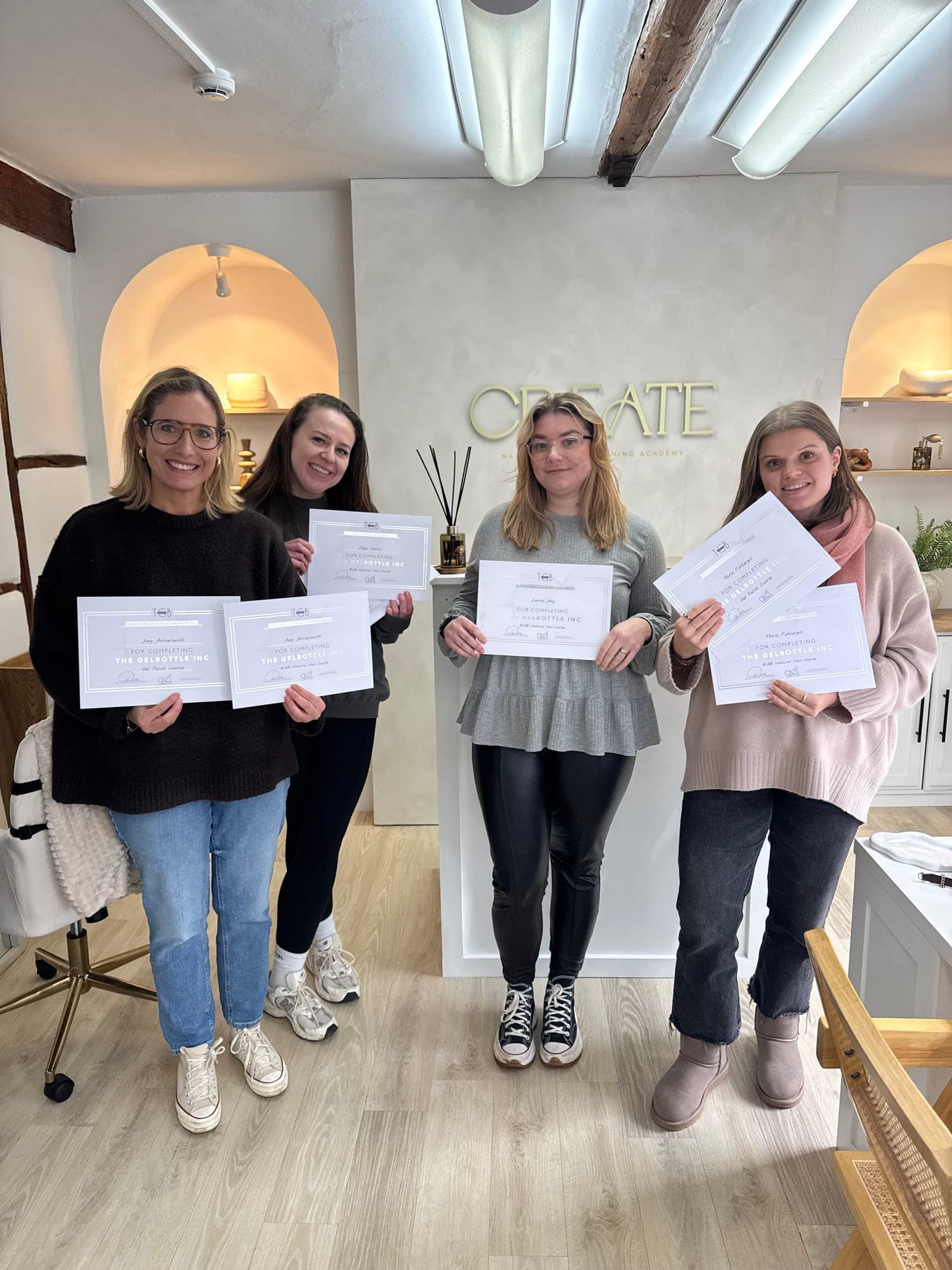Four smiling CREATE students holding their course completion certificates